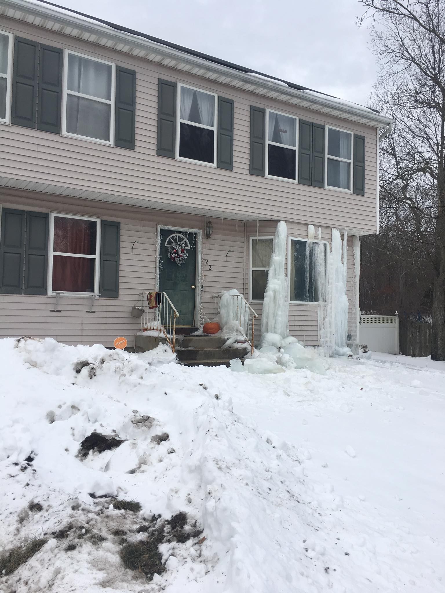 A house with a lot of snow on the ground in front of it.
