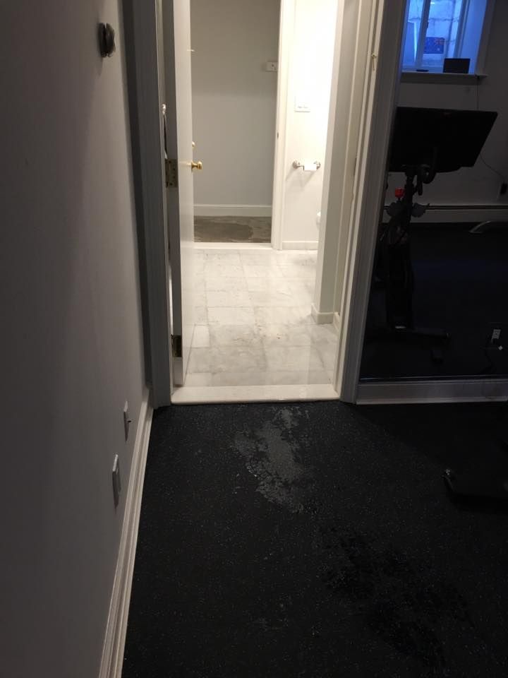 A hallway with a black carpet and a doorway leading to a bathroom.