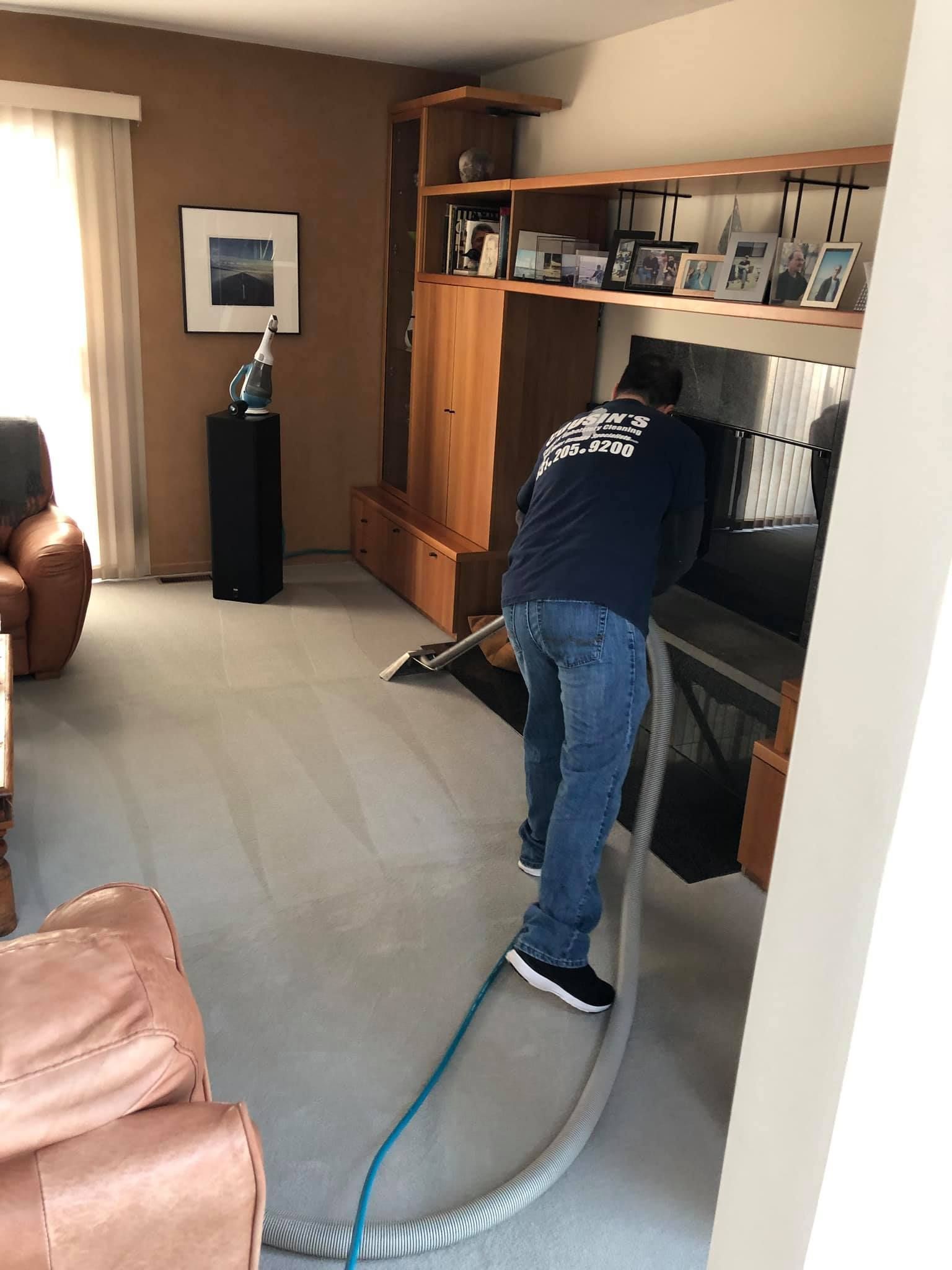 A man is cleaning the carpet in a living room with a vacuum cleaner.