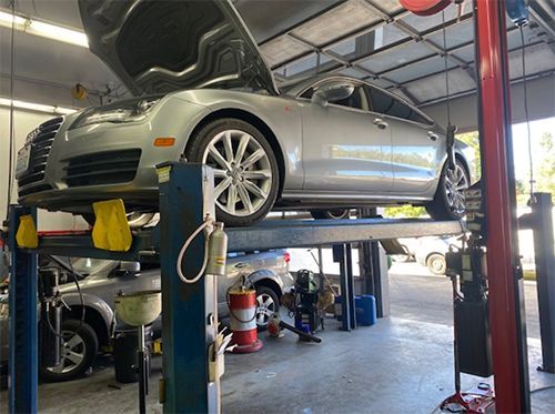 A car is sitting on a lift in a garage with the hood up.