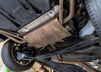 The underside of a car with a exhaust pipe and a tire.