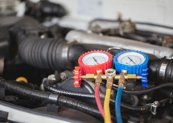 A close up of a car engine with two gauges attached to it.