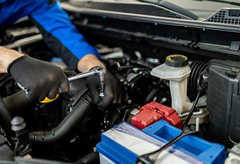 A man is working on the engine of a car with a wrench.