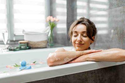 A woman relaxing in a bath and smiling