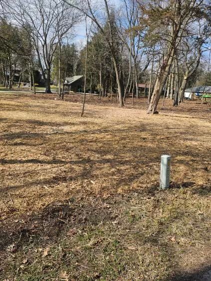 There is a pole in the middle of a field with trees in the background.