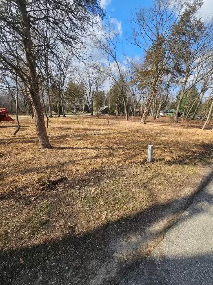 There is a tent in the middle of a field surrounded by trees.