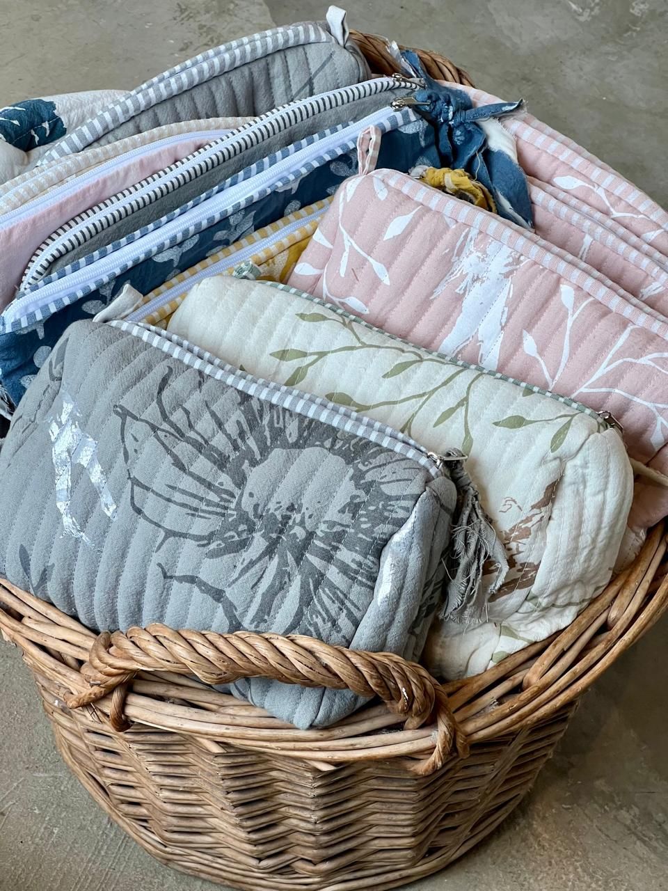 Cesta repleta de bolsitas de tela acolchadas en varios colores pastel.