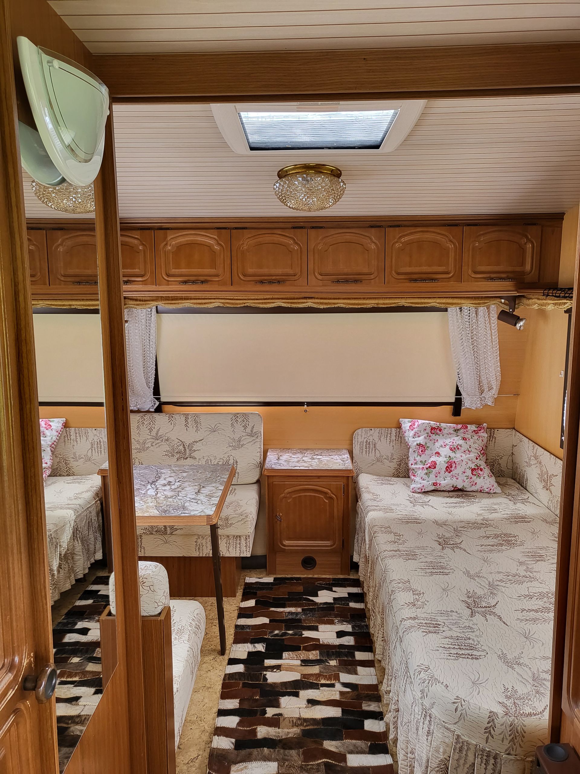 A caravan with two beds , a couch , and a rug.