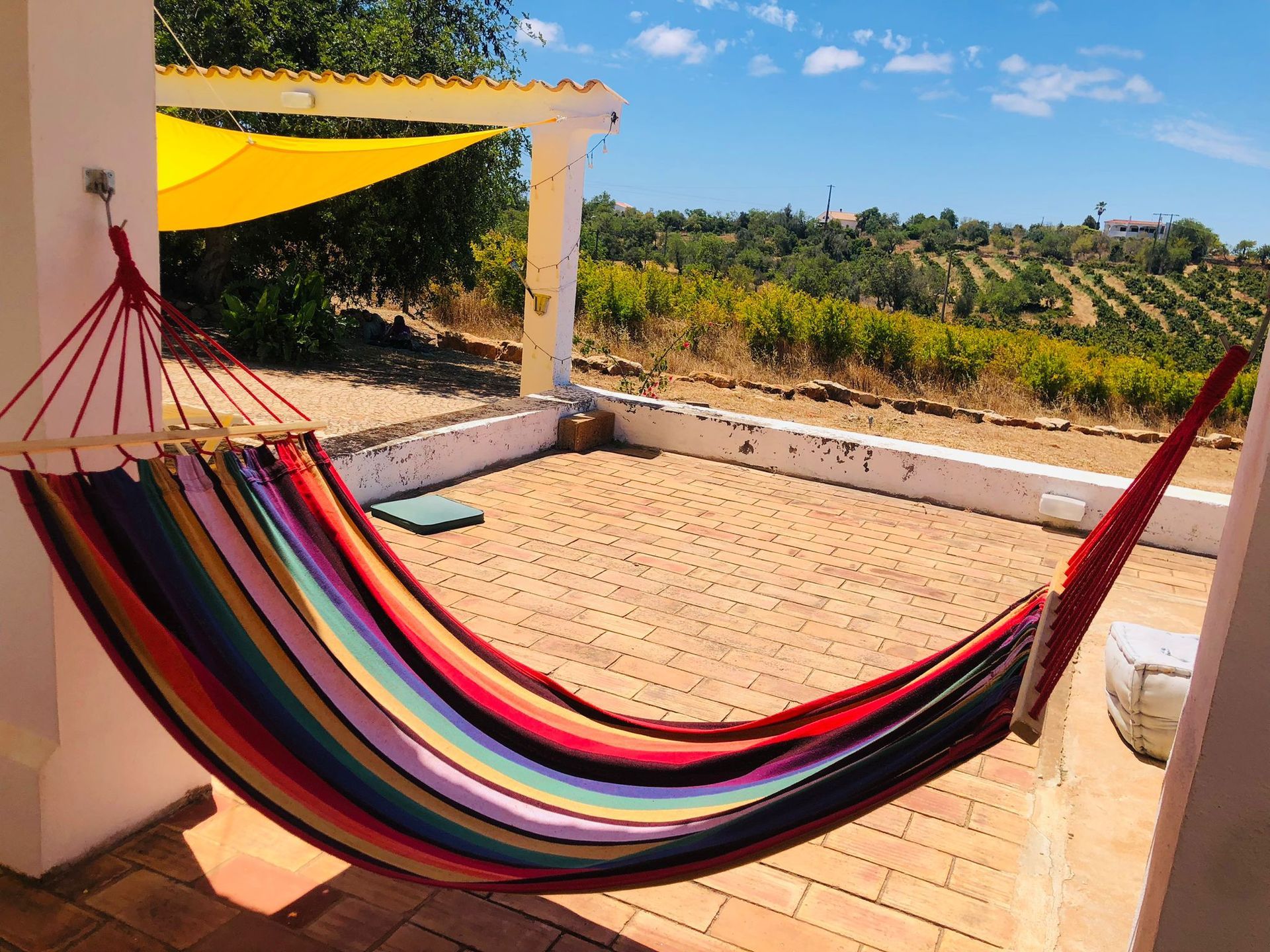 A colorful hammock is sitting on a patio with a view of a vineyard.