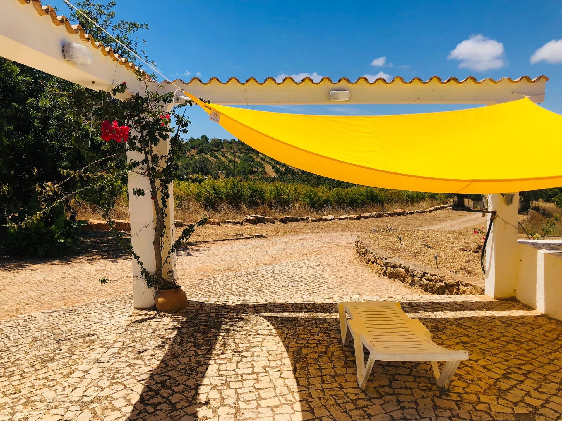 A yellow umbrella is hanging over a stone walkway