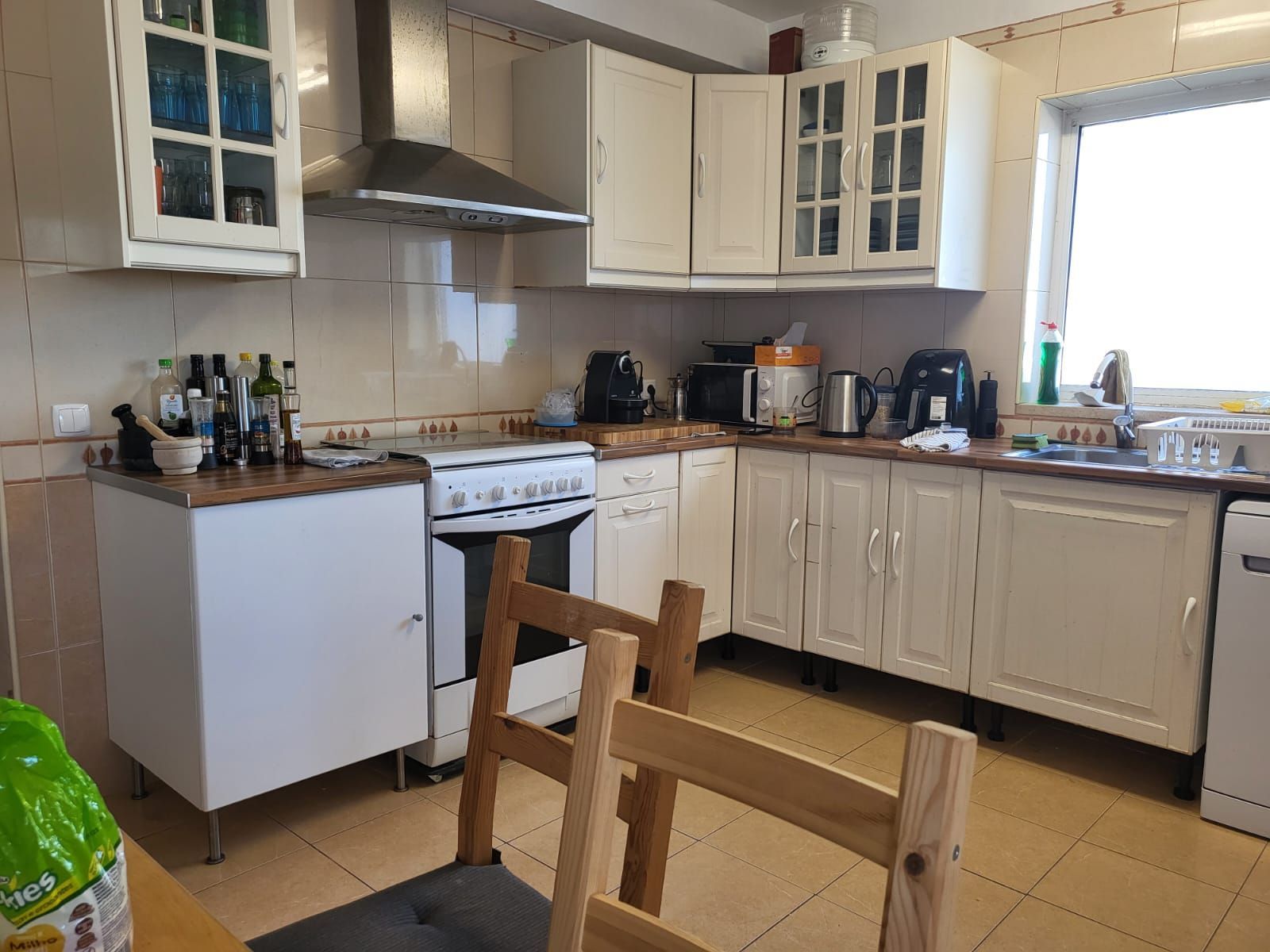 A kitchen with white cabinets , a stove , a sink , and a window.