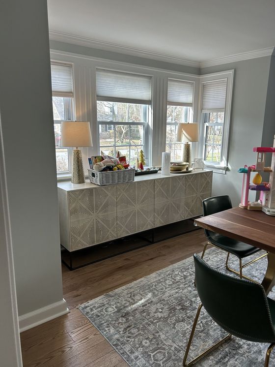 A dining room with a table , chairs , lamps , and a rug.