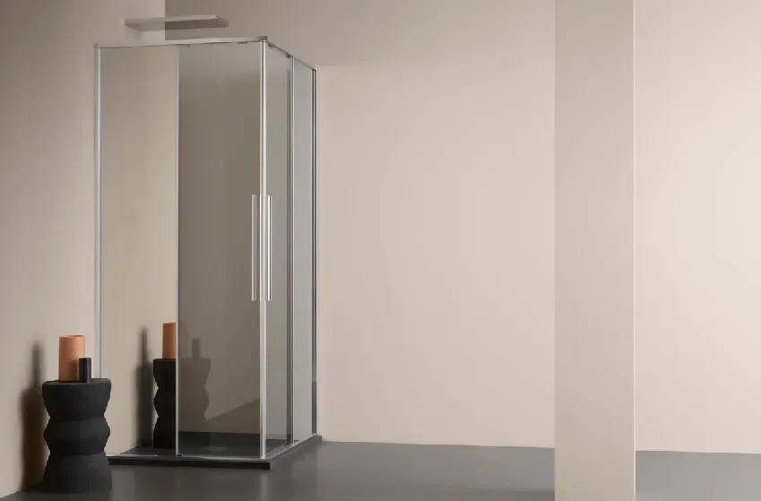 Box doccia in un bagno dai toni neutri. Due oggetti decorativi sono posizionati accanto al box.