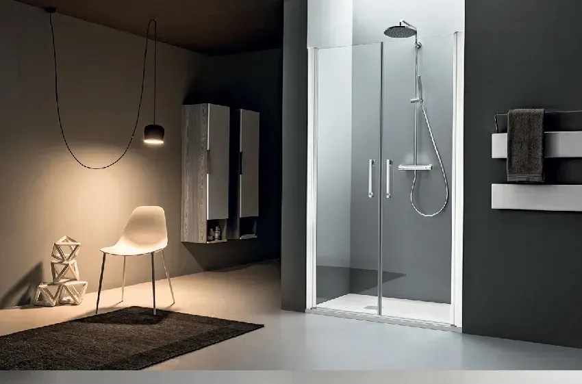Bagno moderno con doccia in vetro, sedia e luce decorativa.