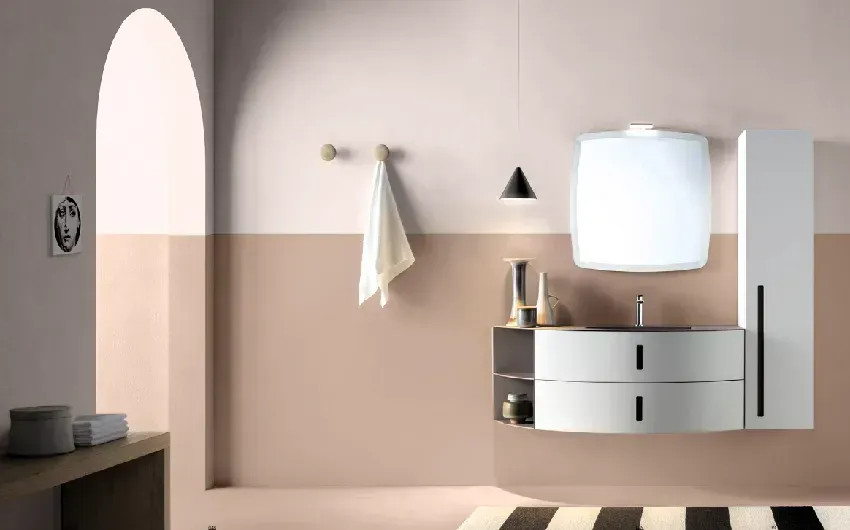 Moderno bagno bianco con pareti rosa e beige, mobile lavabo ovale, specchio e spazio di archiviazione alto.
