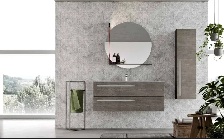 Bagno moderno con parete testurizzata grigia, mobiletto sospeso, specchio rotondo e mobiletto alto.