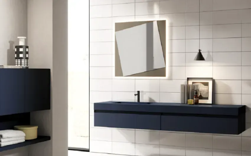 Bagno moderno con mobile lavabo sospeso blu navy, specchio quadrato e pareti piastrellate bianche.