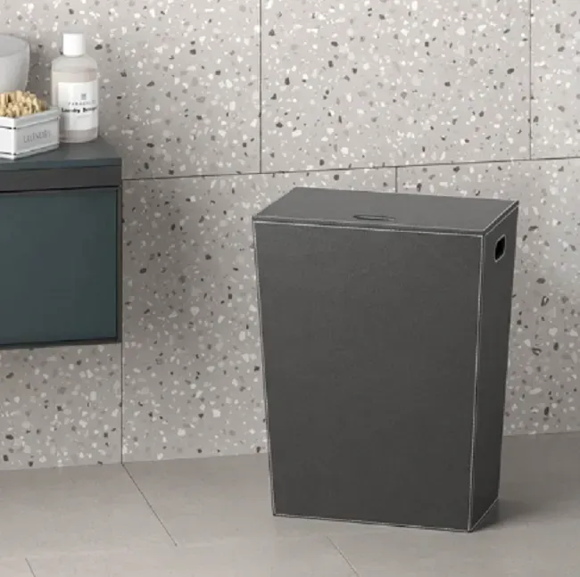 Cesto portabiancheria grigio scuro in un bagno con piastrelle marrone