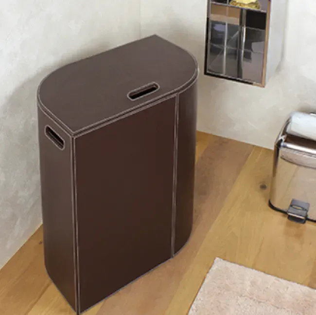 Cesto portabiancheria in pelle marrone con manico ritagliato, in un bagno.