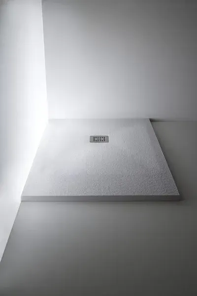 Piatto doccia bianco con scarico, in un bagno minimalista.