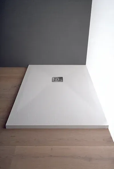 Piatto doccia rettangolare bianco su pavimento in legno chiaro; pareti grigie e bianche.