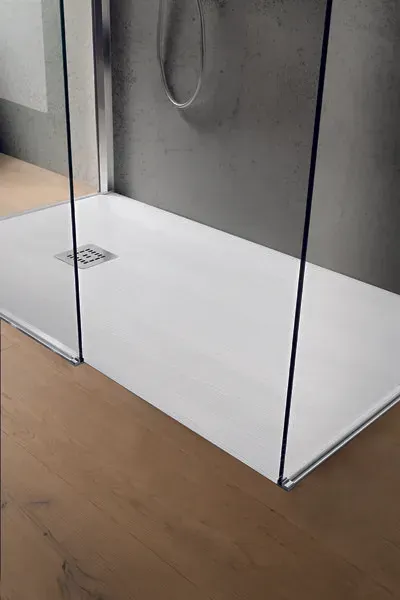 Piatto doccia bianco con cabina in vetro, installato su pavimento in legno.