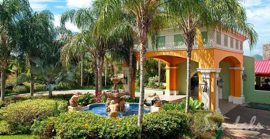 A colorful building with a fountain in front of it surrounded by palm trees.