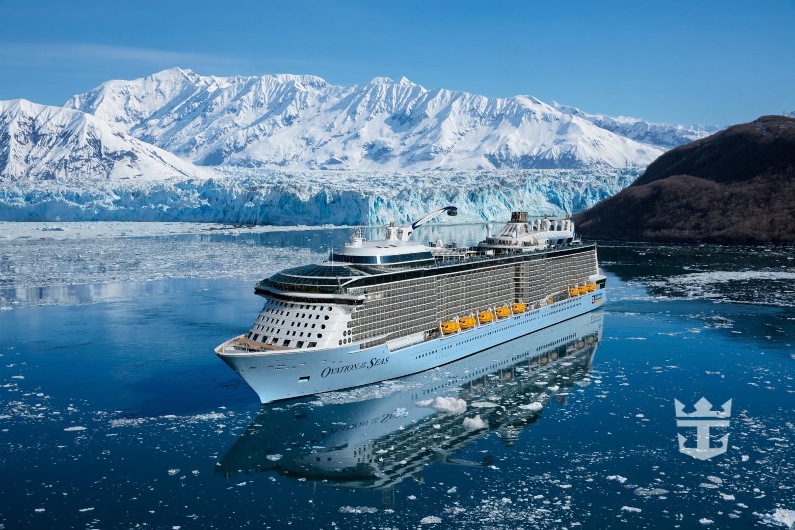 A cruise ship is floating in the water with mountains in the background.