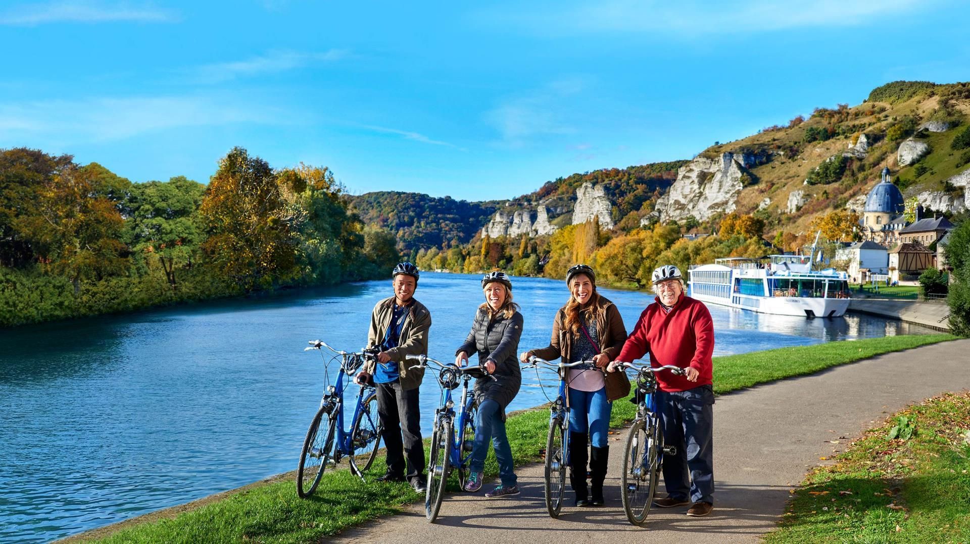 A group of people are standing next to each other on bicycles by a river.
