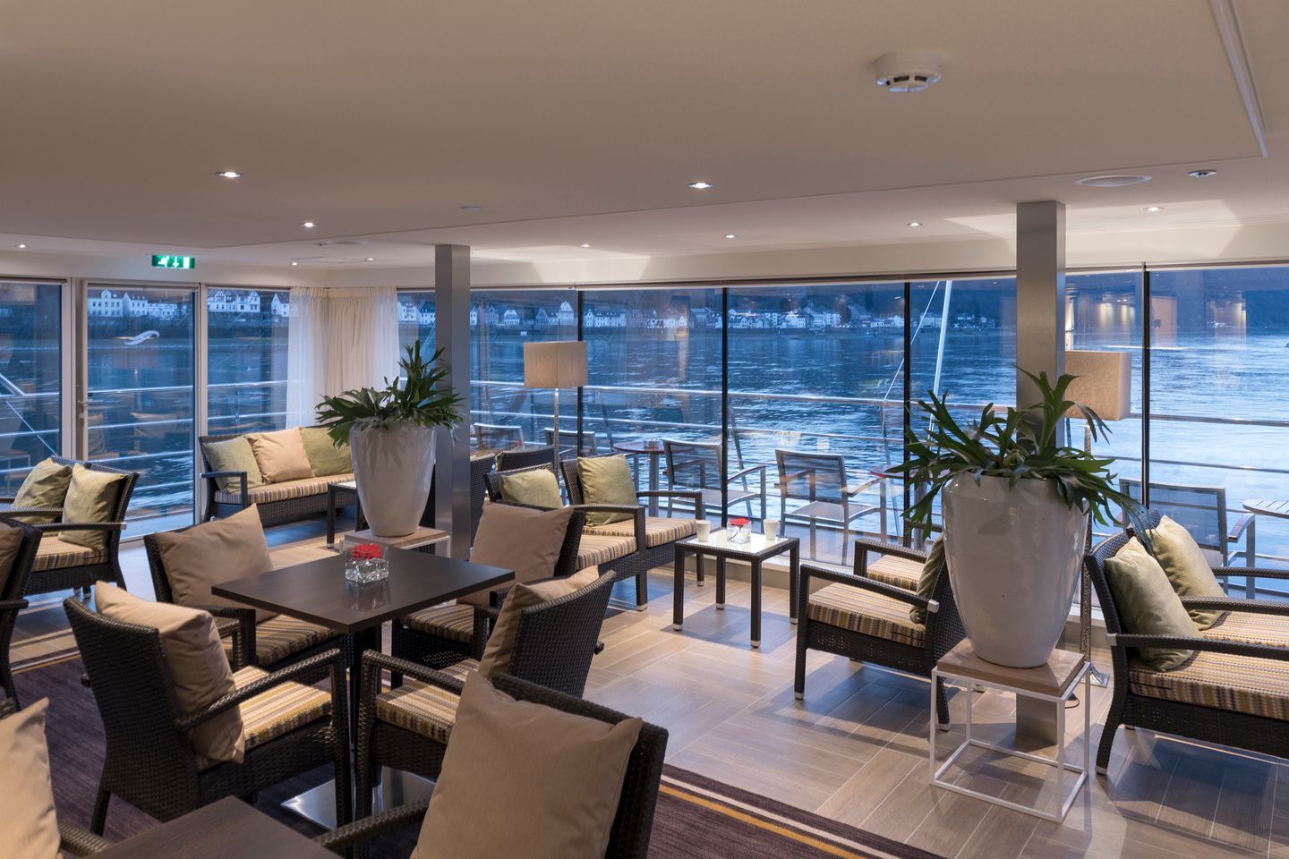 A living room filled with furniture and tables with a view of the water.