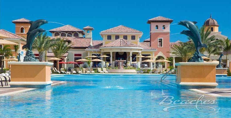 A large swimming pool with dolphins in front of a large house