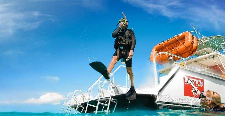 A man is standing on the side of a boat in the ocean.