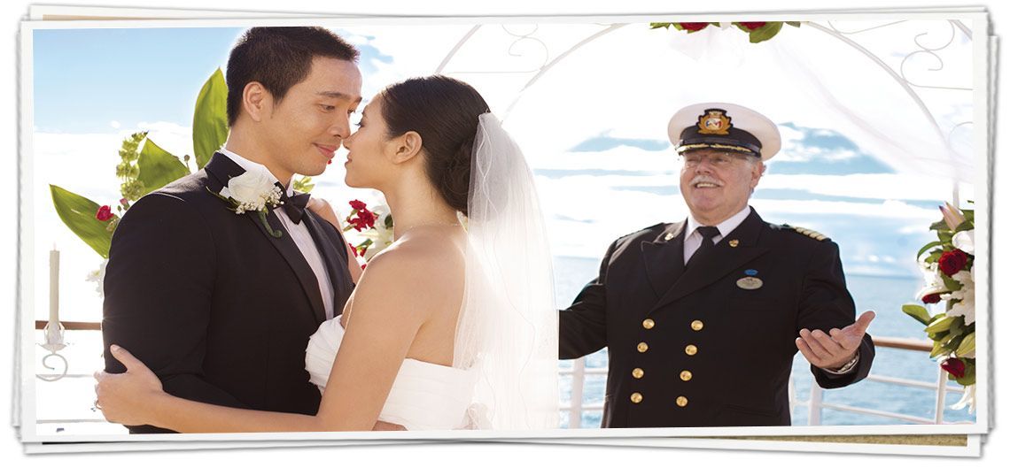 A bride and groom are kissing in front of a man in a uniform.