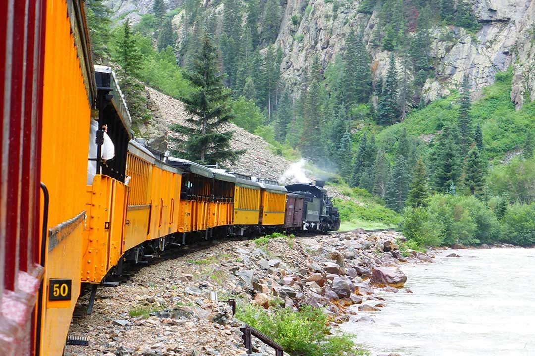 A train is going down the tracks next to a river.