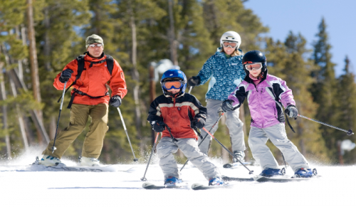 A family is skiing down a snow covered slope.