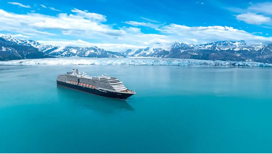 A cruise ship is floating on top of a lake with mountains in the background.