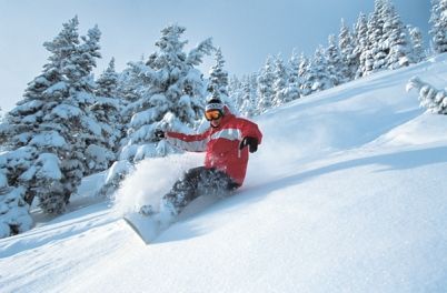 A person is snowboarding down a snow covered hill.