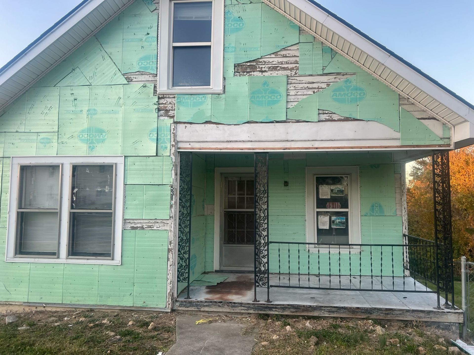 Weathered mint-green house with peeling paint and a small front porch and steps