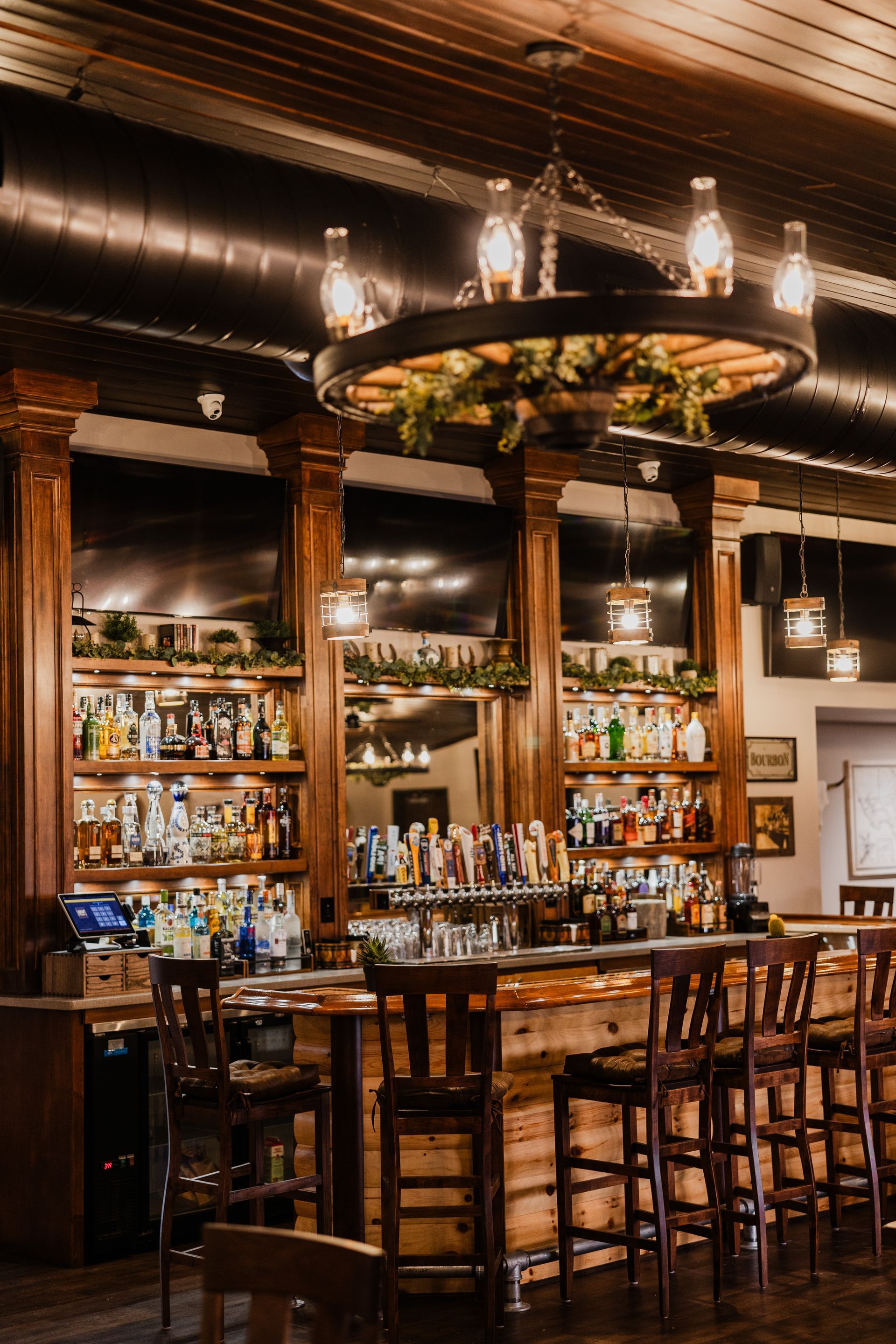 A bar filled with lots of alcohol and a chandelier hanging from the ceiling.