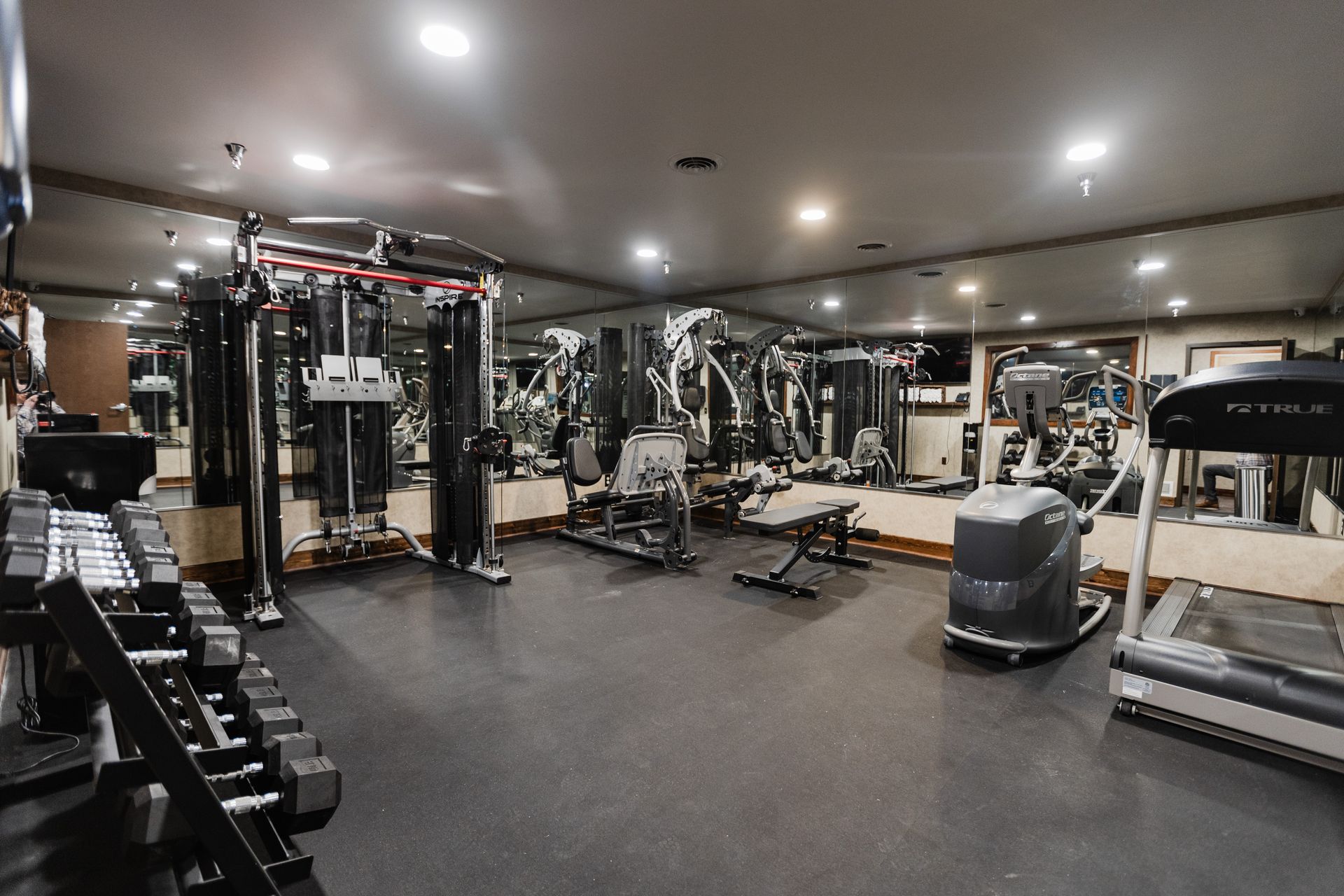 A large gym with a treadmill , dumbbells , and other equipment.
