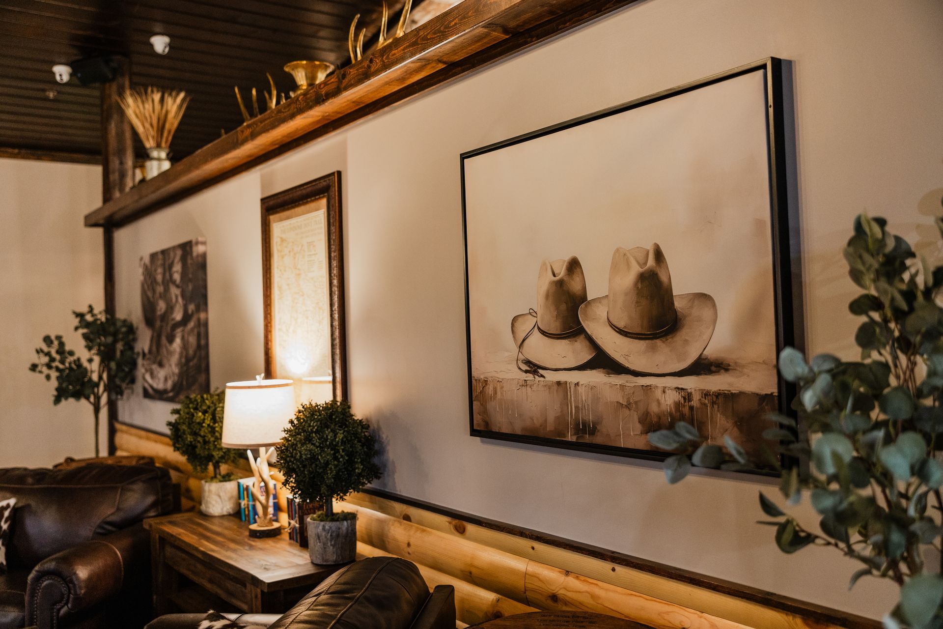A living room with a painting of two cowboy hats on the wall.