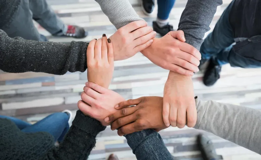 Un grupo de personas junta sus manos formando un círculo.