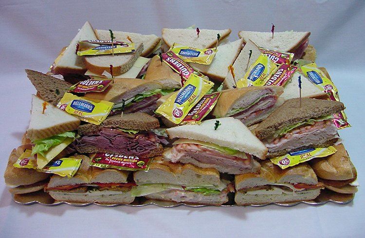 A tray of sandwiches with mustard packets on them