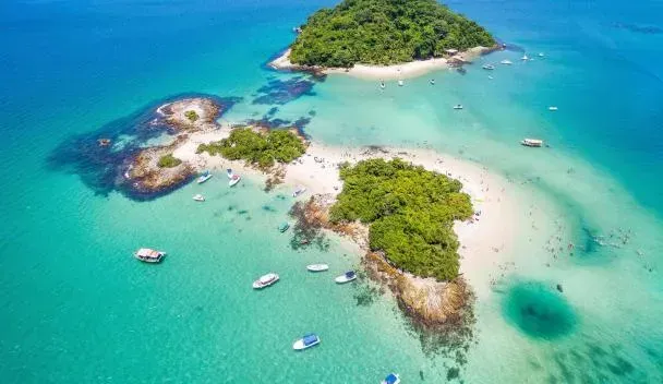 Islas tropicales con aguas turquesas, barcos y exuberante vegetación verde.