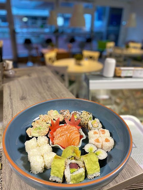 Assiette de sushis sur un comptoir en bois avec un arrière-plan de restaurant flou.