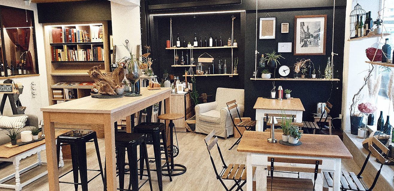 Intérieur d'un café avec des tables en bois, des étagères avec des bouteilles et un coin salon.