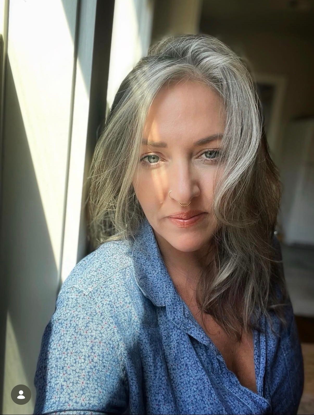 Woman in athletic wear, hands in prayer pose, in a bright, wooden-floored studio.
