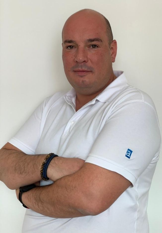 Ein Mann mit verschränkten Armen und einem weißen Poloshirt