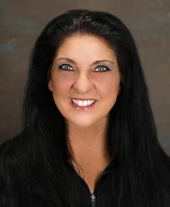 A woman with long black hair is smiling for the camera.