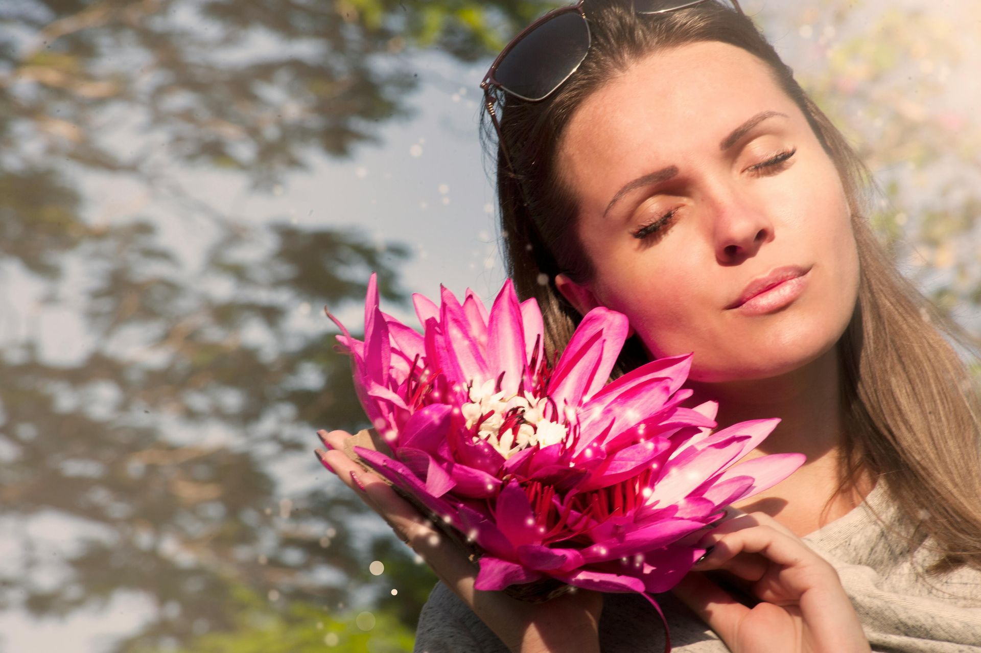 A woman is holding a large pink flower in her hands.